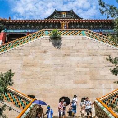 Tourists explore the historic architecture of Summer Palace in Beijing under a vibrant summer sky.