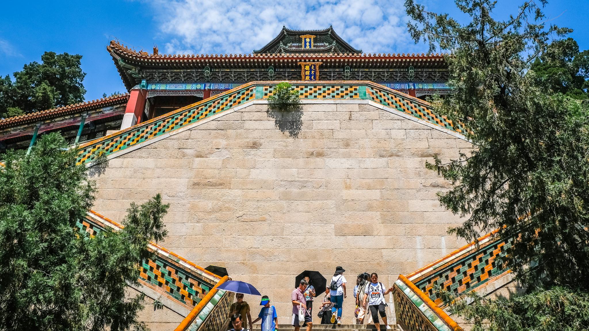 Tourists explore the historic architecture of Summer Palace in Beijing under a vibrant summer sky.